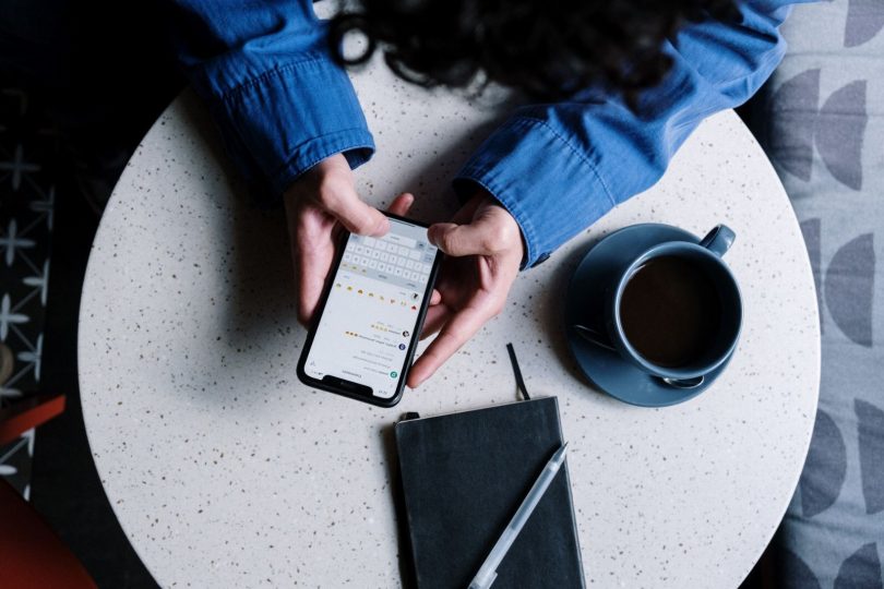 Pessoa usando smartphone para escrever avaliação online de estabelecimento