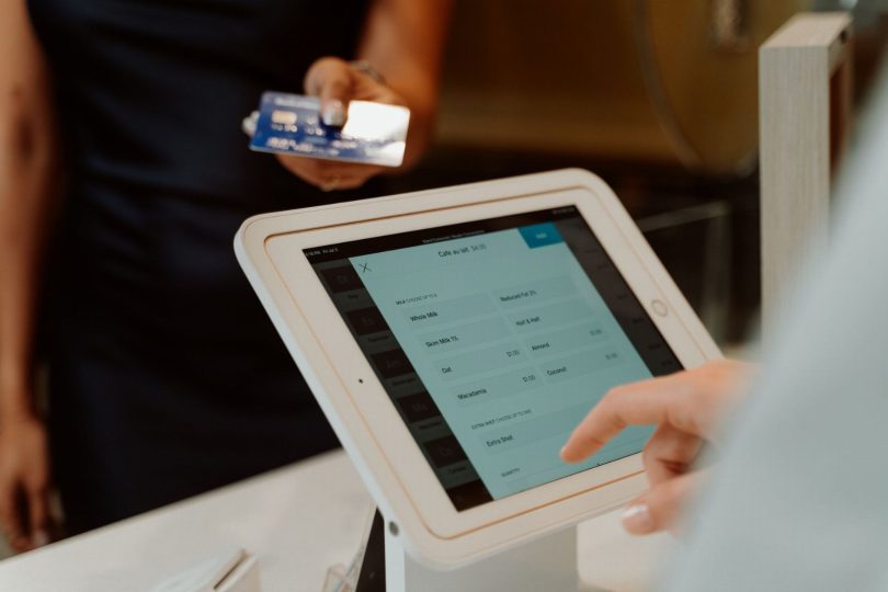 Pessoa avaliando serviço com cinco estrelas usando tablet dentro de estabelecimento
