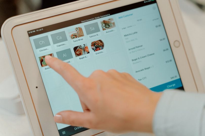 Empresário solicitando avaliação no Google usando tablet em frente à loja