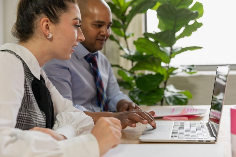 Pessoa analisando avaliações do negócio no laptop com celular e bloco de notas ao lado